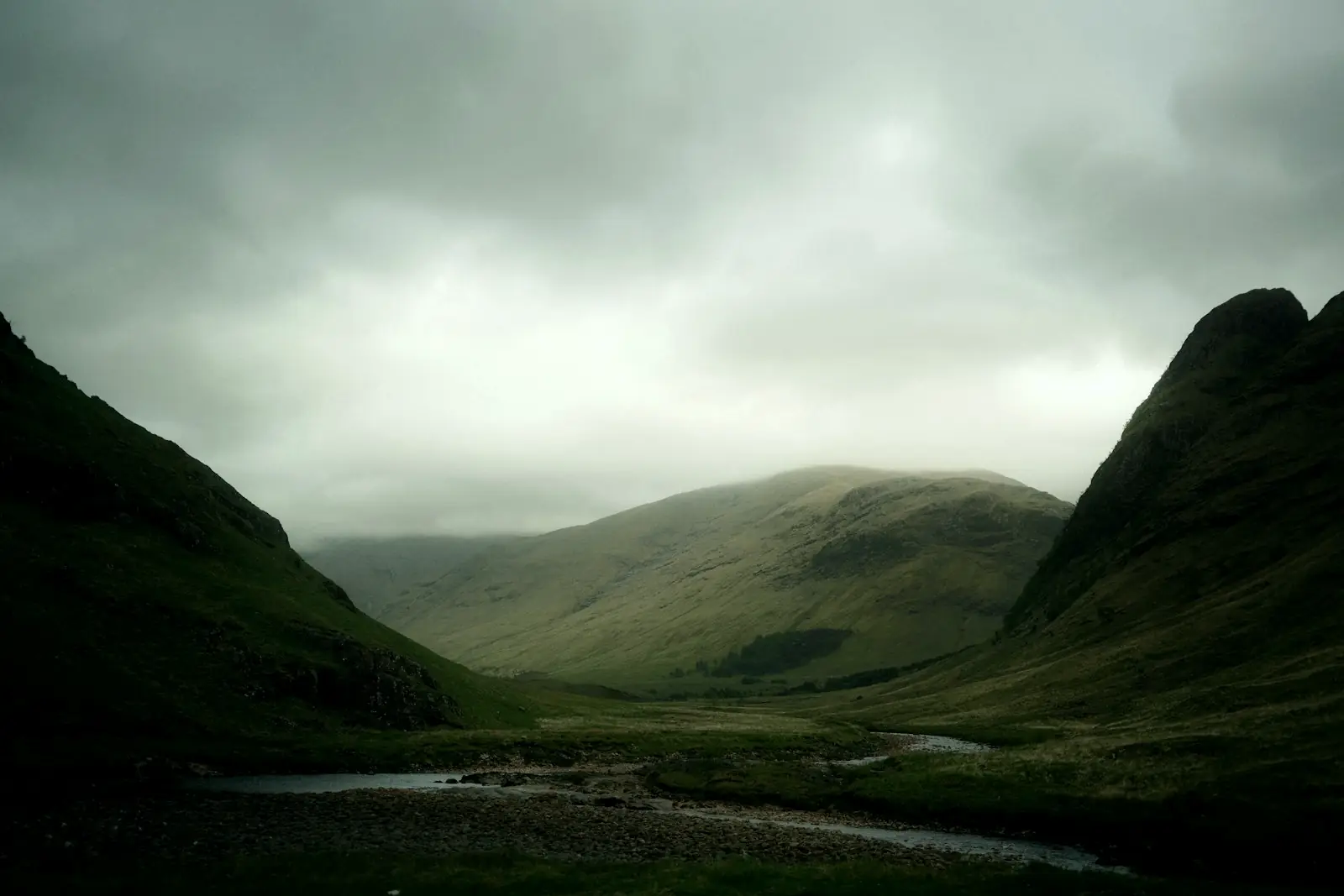 A river running through a green Highland valley under low cloud